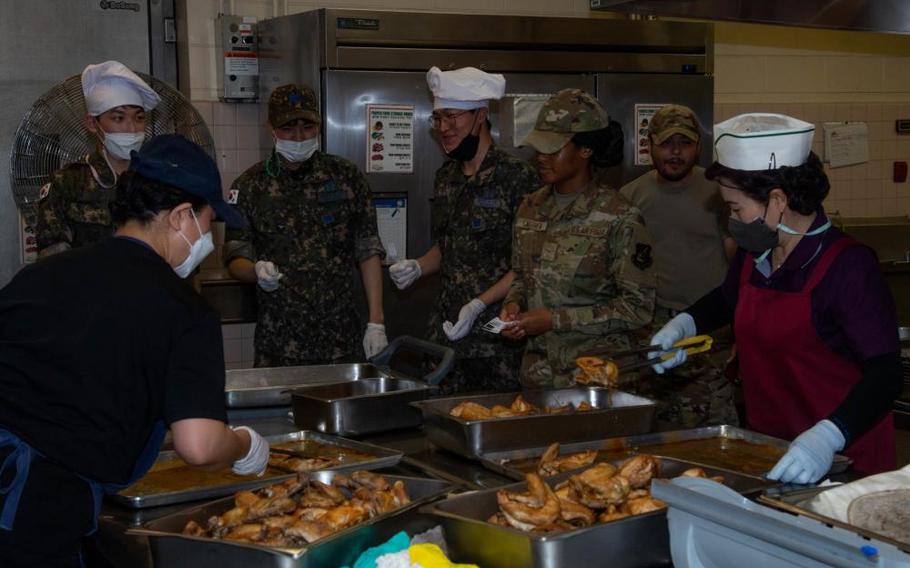 U.S. Air Force and Republic of Korea Air Force service members taste test food during an immersion at Kunsan Air Base, Republic of Korea, June 28, 2022. During the immersion, service members assisted one another in preparing various dishes for a mid-day meal. (U.S. Air Force photo by Senior Airman Shannon Braaten)