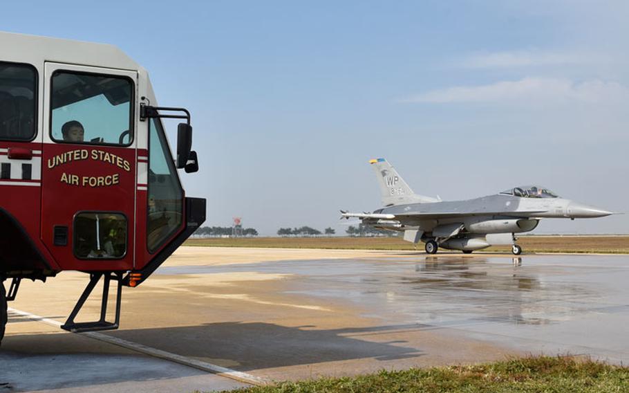 A U.S. Air Force F-16 Fighting Falcon aircraft from the 8th Fighter Wing passes students from the Gunsan Mun Hwa Elementary School during their visit to the 8th Civil Engineer Squadron fire department open house at Kunsan Air Base, Republic of Korea, Oct. 16, 2019. Fire department personnel provided the students with a tour of the fire house, showed them the equipment used to fight fires and taught basic fire safety skills. (U.S. Air Force photo by Tech. Sgt. Joshua Arends)