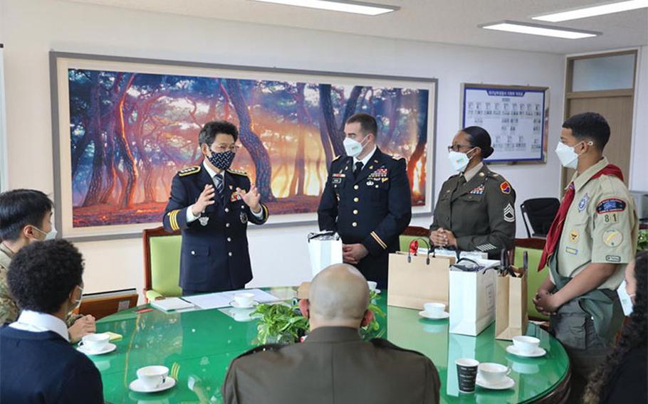 Nam-gu District Police Chief Kap Soo Yi speaks with Maj. Gabriel Bowns, Sgt. 1st Class Gisela Schilling and Azizi Wilkins about their acts of heroism that resulted in a burning building being evacuated with no casualties. Chief Yi presented the trio with traditional Korean gifts in recognition of their selfless acts.