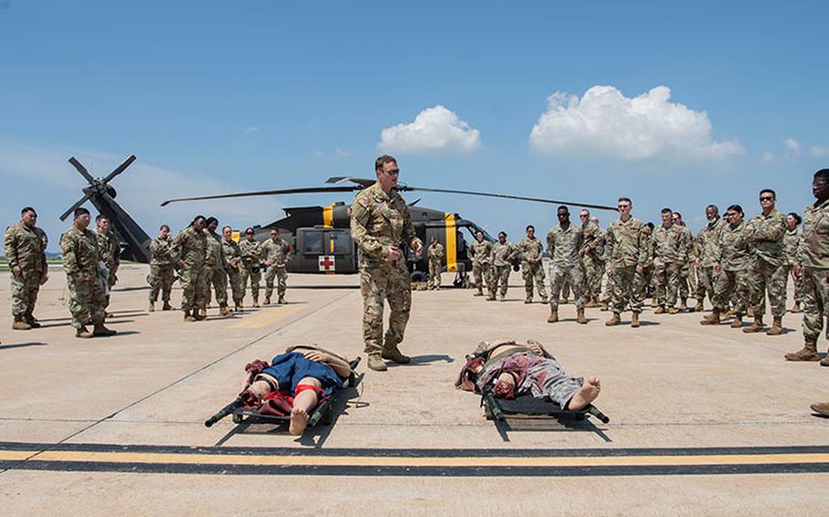 U.S. Army Staff Sgt. Elliot Gottschalk, 2nd Combat Aviation Brigade Charlie Company 3-2 flight paramedic, briefs on litter carrying measures for UH-60 Black Hawks during a training event at Kunsan Air Base, Republic of Korea, Aug. 18, 2022. The 8th MDG is devoted to optimizing the installation’s readiness in preparation of follow-on forces. (U.S. Air Force photo by Staff Sgt. Sadie Colbert)