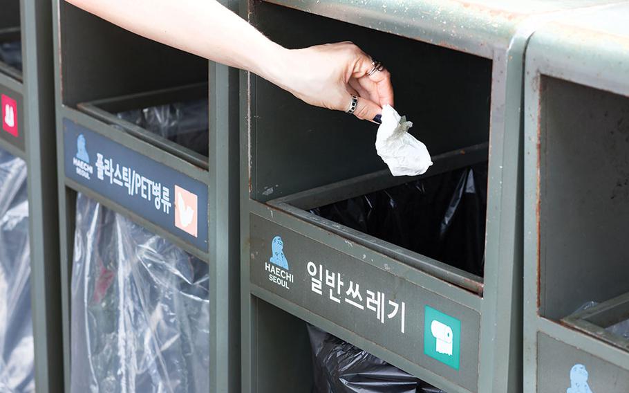 A person is throwing trash into a dustbin.