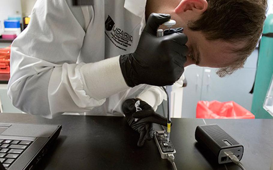 Dr. Peter Larson loads an Oxford Nanopore MinION sequencer in support of COVID-19 sequencing assay development at the U.S. Army Medical Research Institute of Infectious Diseases, Fort Detrick, Maryland. (Photo by John Braun Jr., USAMRIID.)