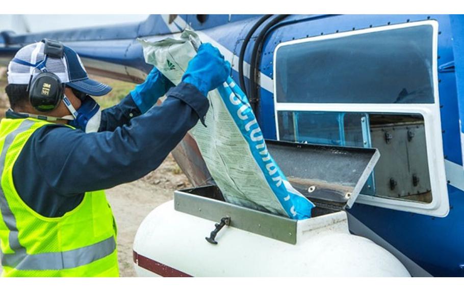 A contractor loads mosquito control pellets onto a helicopter spreader for aerial spraying at Marine Corps Base Camp Pendleton, California. (Photo by Marine Lance Cpl. Kerstin Roberts)