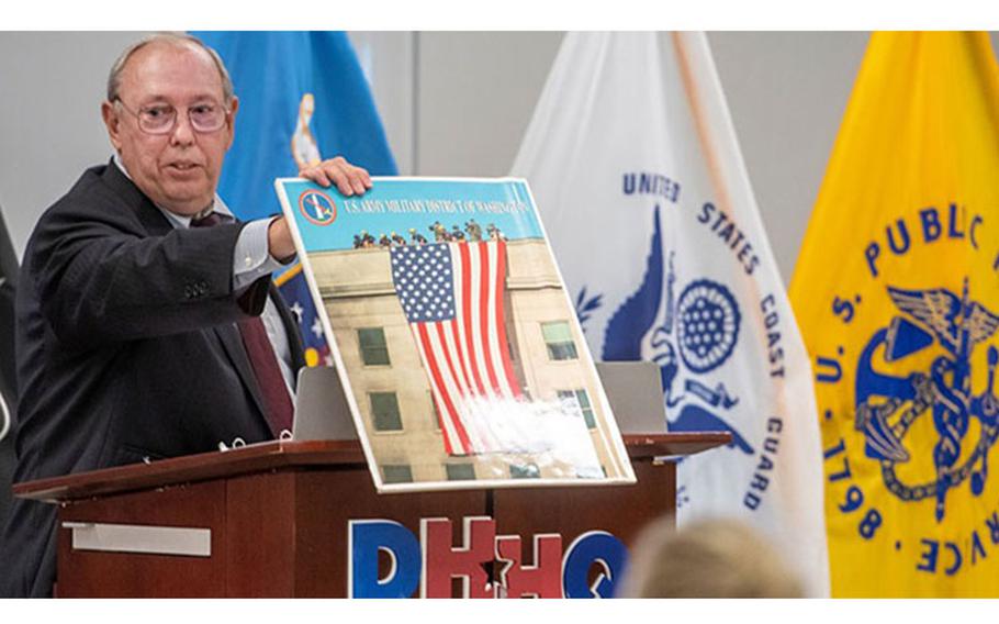 Richard Breen, director of strategic communications for the assistant secretary of defense for health affairs and the office of the director of the Defense Health Agency, displays the iconic 9/11 photo of the American flag draped down the side of the damaged Pentagon. Breen was the featured speaker at the Defense Health Agency’s Patriot’s Day remembrance ceremony at the Defense Health Headquarters on Sept. 9, 2022. (Photo: Robbie Hammer, MHS Communications)