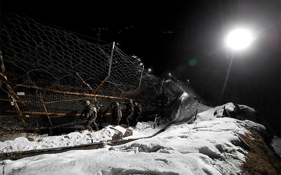 The soldiers are carrying out a night patrol mission along the iron fence.