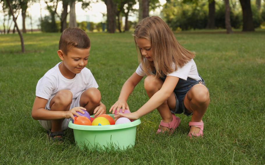 Kids with plastic pool of water balloons