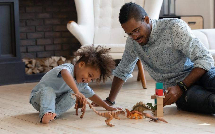 Child and parent playing with dinosaur toys