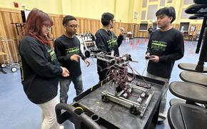 Minseo Harthausen, left, Mathew Huang, center, and Kayla Collins set up a Science Day welcome table in the gym at Humphreys High School at Camp Humphreys.