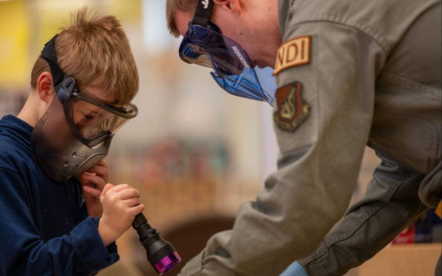 U.S. Air Force Senior Airman Gavin Woods, 51st Maintenance Squadron non-destructive inspection journeyman, shows an Osan Elementary School student how to check for fractures in metal objects during career day at Osan Air Base, Republic of Korea, March 15, 2024.
