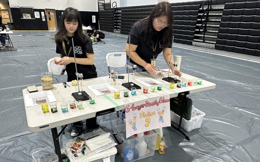 Mieka Sabia, left, and Sophia Baek prepare their Science Day activity in the Humphreys High School gym at Camp Humphreys.