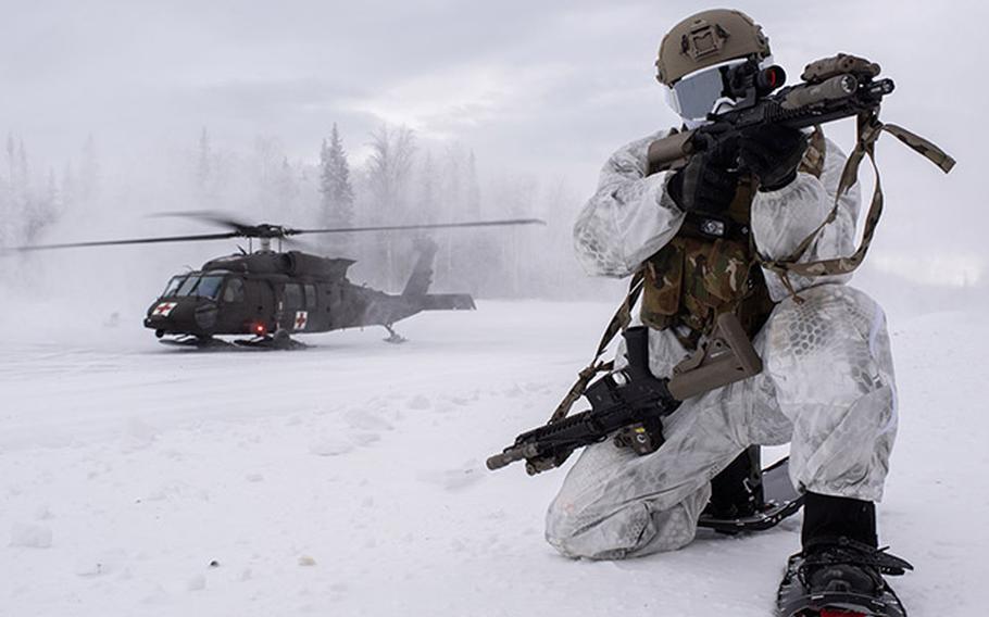 Soldier in the snow with helicopter in the background.