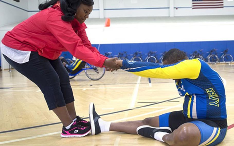 Ida Malone helps her husband, Navy Chief Petty Officer Averill Malone, stretch before bicycling during the Navy’s training camp for Department of Defense’s Warrior Games at Ventura County Naval Station Port Hueneme in Oxnard, California. Malone is the caregiver for her husband, who suffers from post-traumatic stress disorder. The new electronic Caregiver Resource Directory, from the Defense Health Agency, provides caregivers with thousands of resources available at their fingertips. (Photo by EJ Hersom)