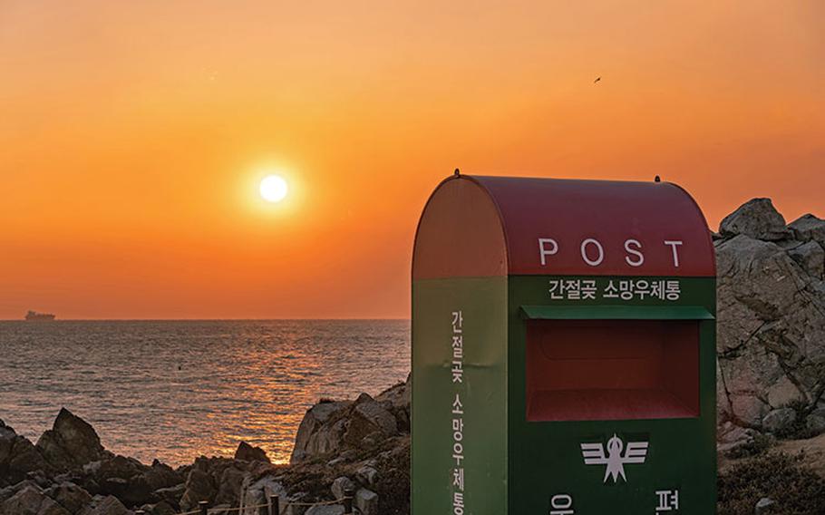 sunrise by the shore and there is a postbox.