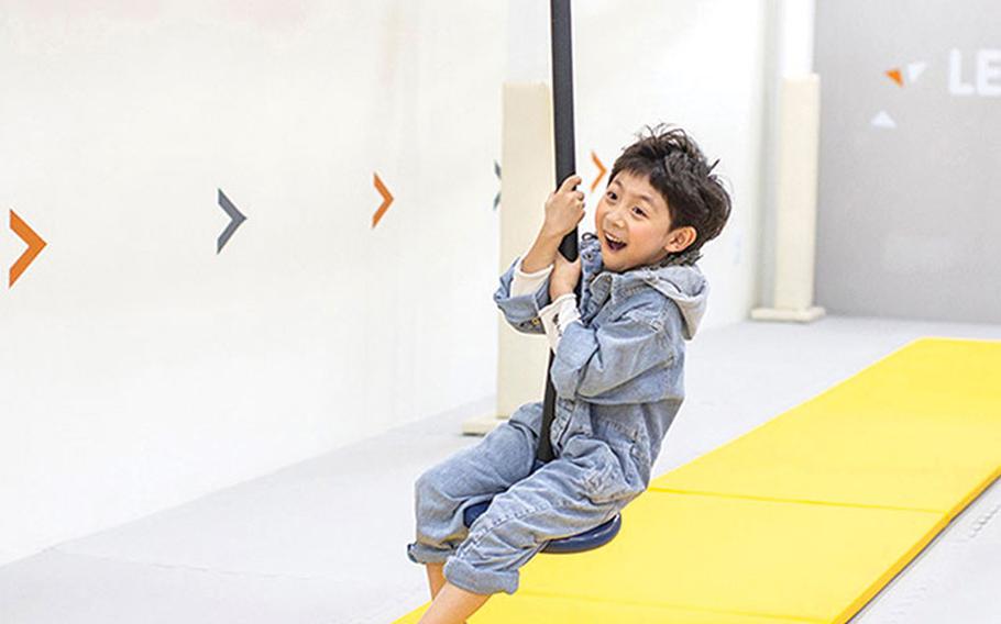 A boy is enjoying playground equipment with a rope.