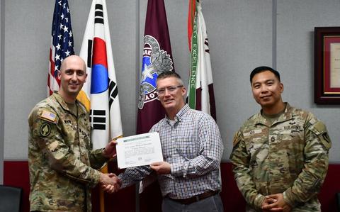 Photo Of Wally Edwards, center, safety and occupational health manager for U.S. Army Medical Logistics Command, presents the safety excellence streamer award to the U.S. Army Medical Materiel Center-Korea on April 22 at Camp Carroll, Republic of Korea. Receiving the award are USAMMC-K Commander Lt. Col. Nathan Wagner, left, and Master Sgt. Jojo Ada, senior enlisted adviser.