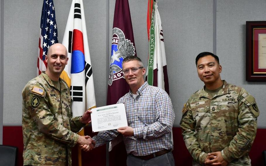 Wally Edwards, center, safety and occupational health manager for U.S. Army Medical Logistics Command, presents the safety excellence streamer award to the U.S. Army Medical Materiel Center-Korea on April 22 at Camp Carroll, Republic of Korea. Receiving the award are USAMMC-K Commander Lt. Col. Nathan Wagner, left, and Master Sgt. Jojo Ada, senior enlisted adviser.
