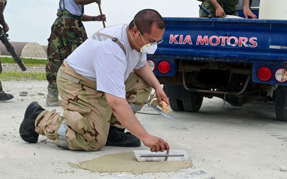 U.S. Air Force Staff Sgt. Luis Romano smooths a concrete patch.