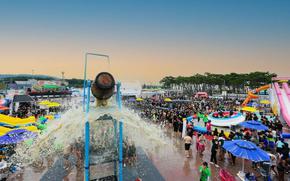 Water is coming out of a huge wooden bucket located at a high place during Boryeong Mud Festival.