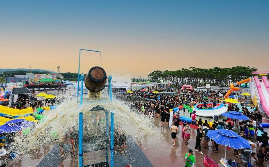 Water is coming out of a huge wooden bucket located at a high place during Boryeong Mud Festival.