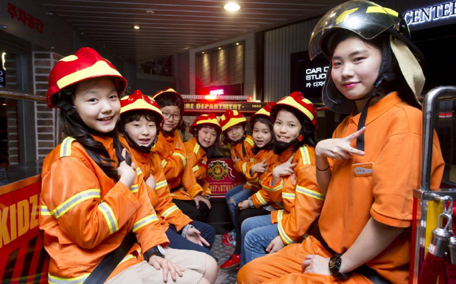 Kids with firefighters’ costumes pose for a photo.