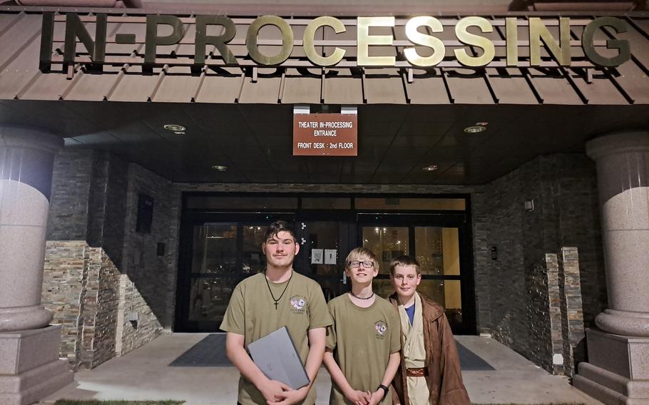 Three people are standing in front of the in-processing building.