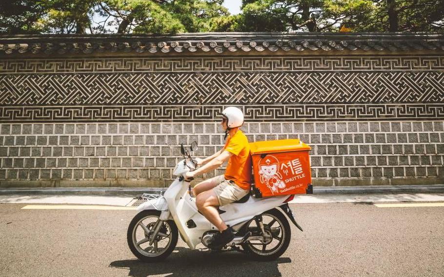 A deliveryman driving a motorcycle.