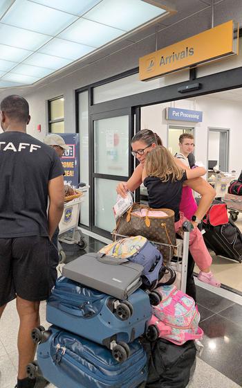 Some people stand in front of the Arrivals gate.