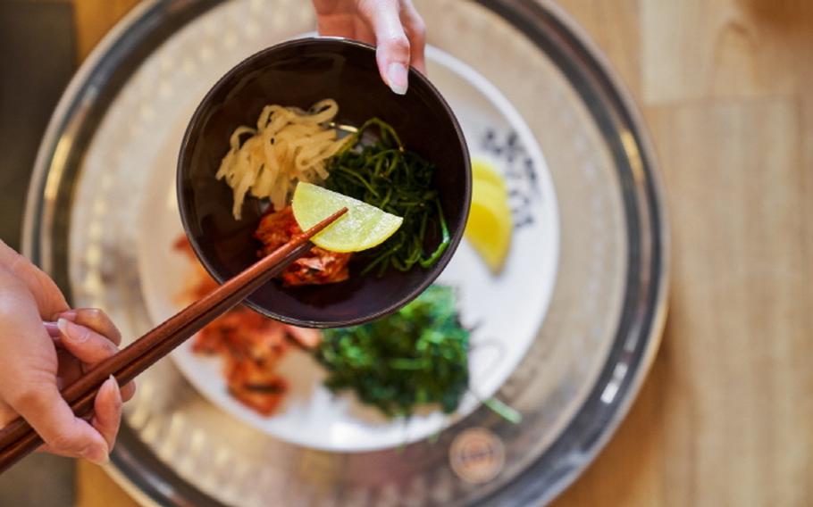 A person is picking a pickle with chopsticks.