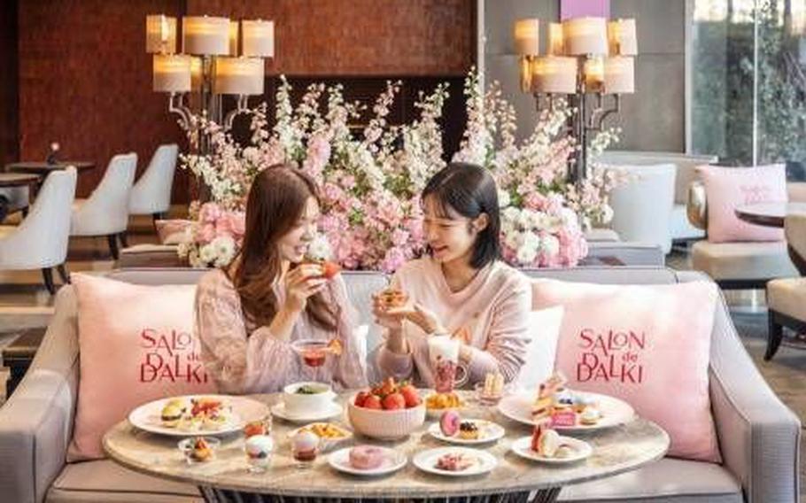 two women are enjoying strawberry dishes and beverages at the hotel.