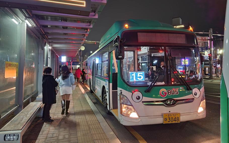 People are taking a Green Bus at night.