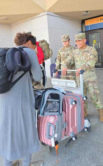 People are carrying luggage outside the airport.