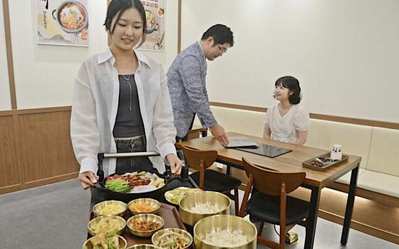 Three people prepare to eat.