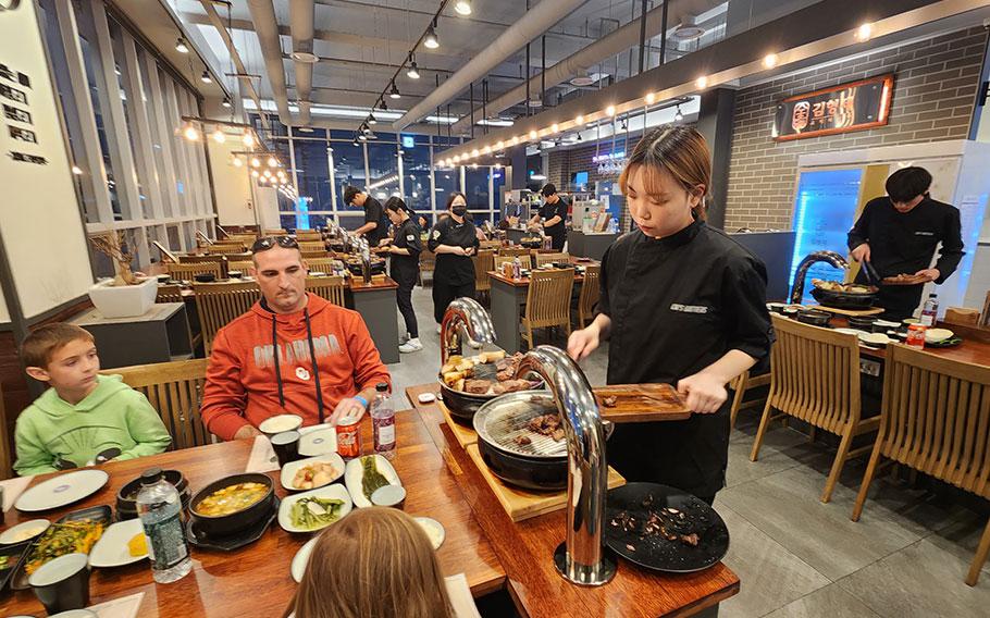 a staff member grilling meats beside the customers’ table.