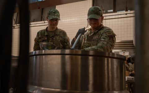 Photo Of Senior Airman Taylor Bennett and Senior Airman Mackenzie Damian cook scrambled eggs in the kitchen.