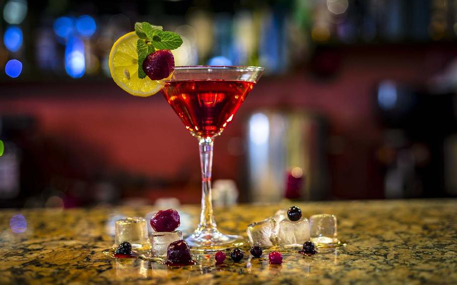 A cocktail in a cocktail glass decorated with fruits such as a slice of lemon.