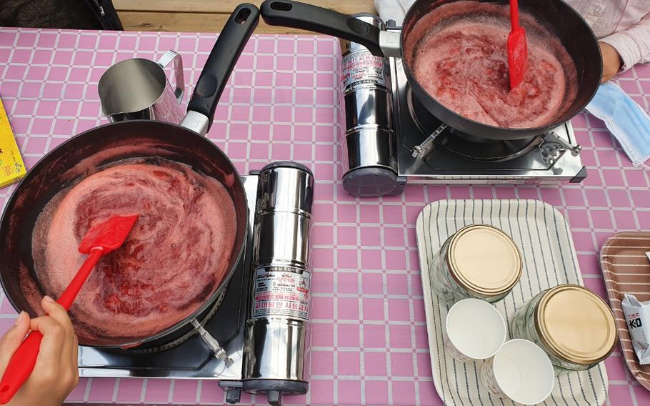 two people are making strawberry jam.