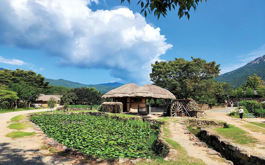 One -story house with a straw-thatched roof. Mountains can be seen.