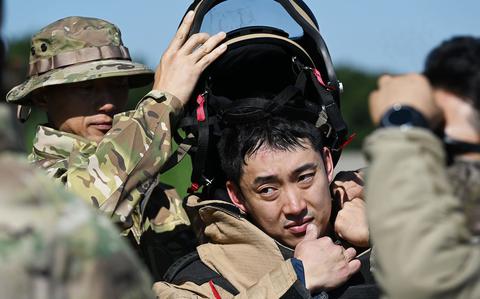 Photo Of Senior Master Sgt. Park Jeong Hwan removes the bomb suit helmet from Master Sgt. Lee Seung Ho.