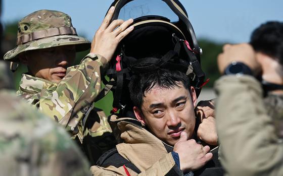 Senior Master Sgt. Park Jeong Hwan removes the bomb suit helmet from Master Sgt. Lee Seung Ho.