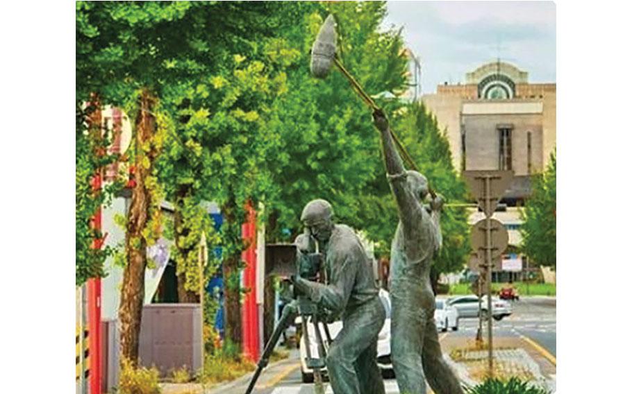 Two statues: one is a camera and the other is recording sound.