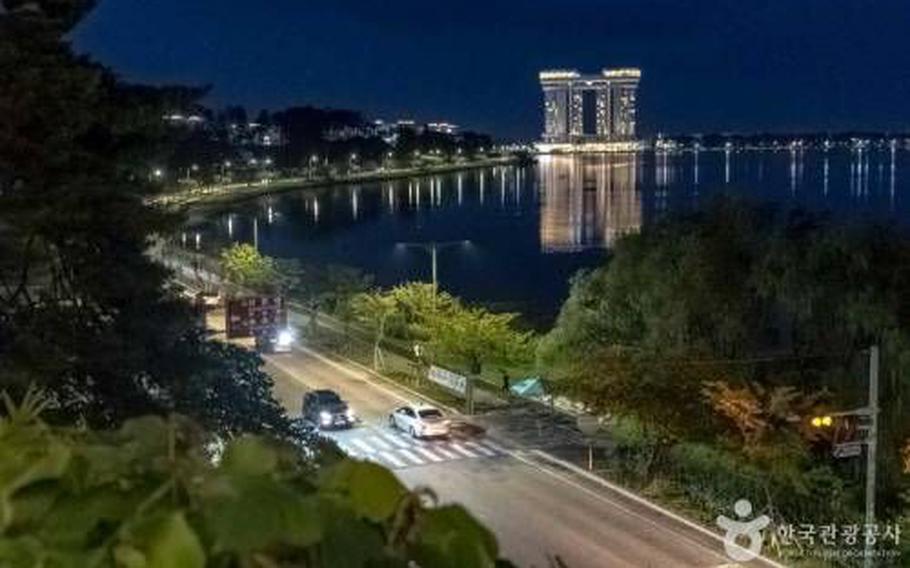 A photo of Gyeongpoho Lake taken from a high place. Some cars drive on the road beside the lake.
