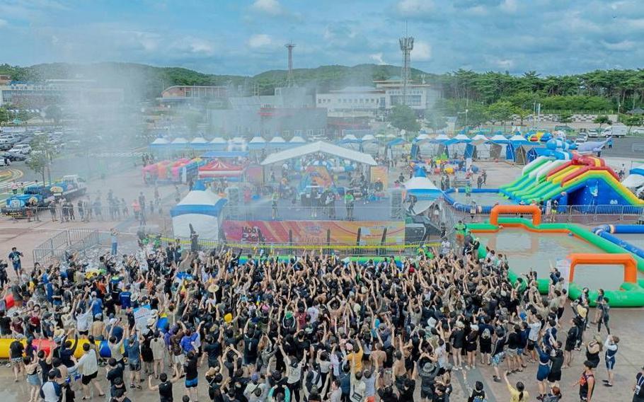 Participants are standing in front of a stage at the Boryeong Festival.