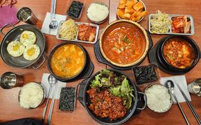 some korean dishes are on the table with chopsticks and spoons.