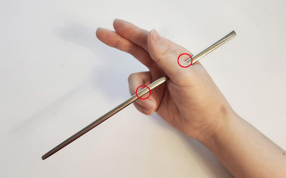 Place the upper part of the first chopstick between the thumb and index finger and put the lower part on a ring finger.