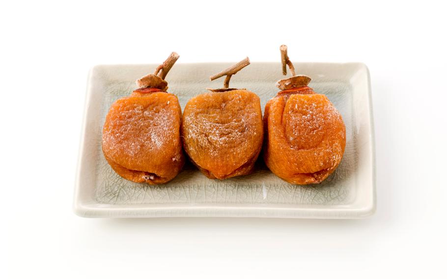 three dried persimmons on a dish.