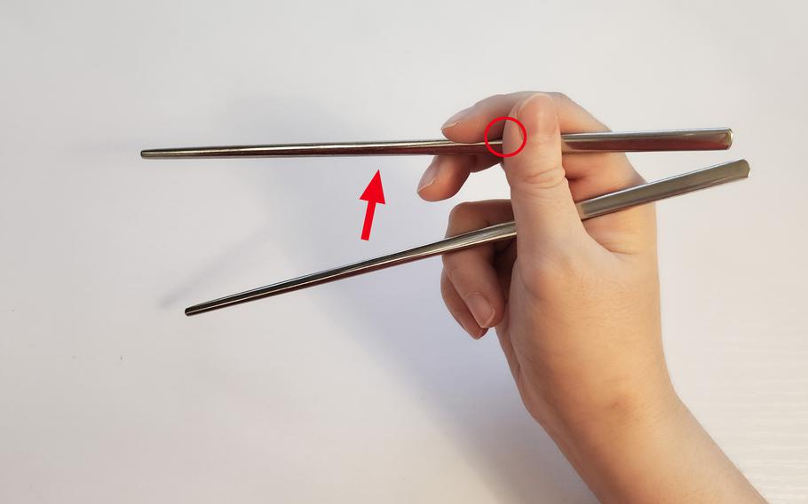 You don’t have to move the first chopstick. Open and close the second chopstick to pick up food by using the index and middle finger. 