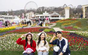 three people pose for a photo in front of the garden.