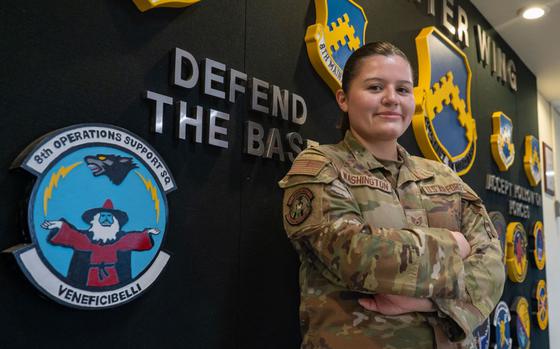 U.S. Air Force Staff Sgt. Alexandria Washington, 8th Operations Support Squadron combat intelligence cell members, poses for a photo with her squadron logo.