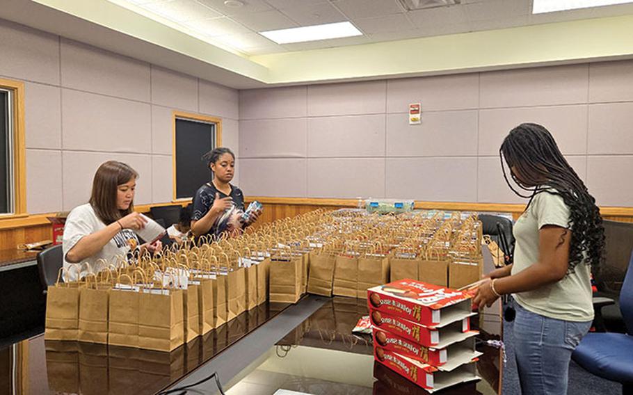 Three staff members are filling paper bags.