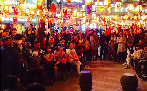 Photo Of Many audience are watching something outside. there are many lanterns above them.